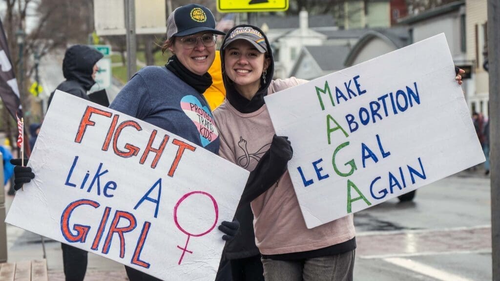Two people holding protest signs about women's rights.