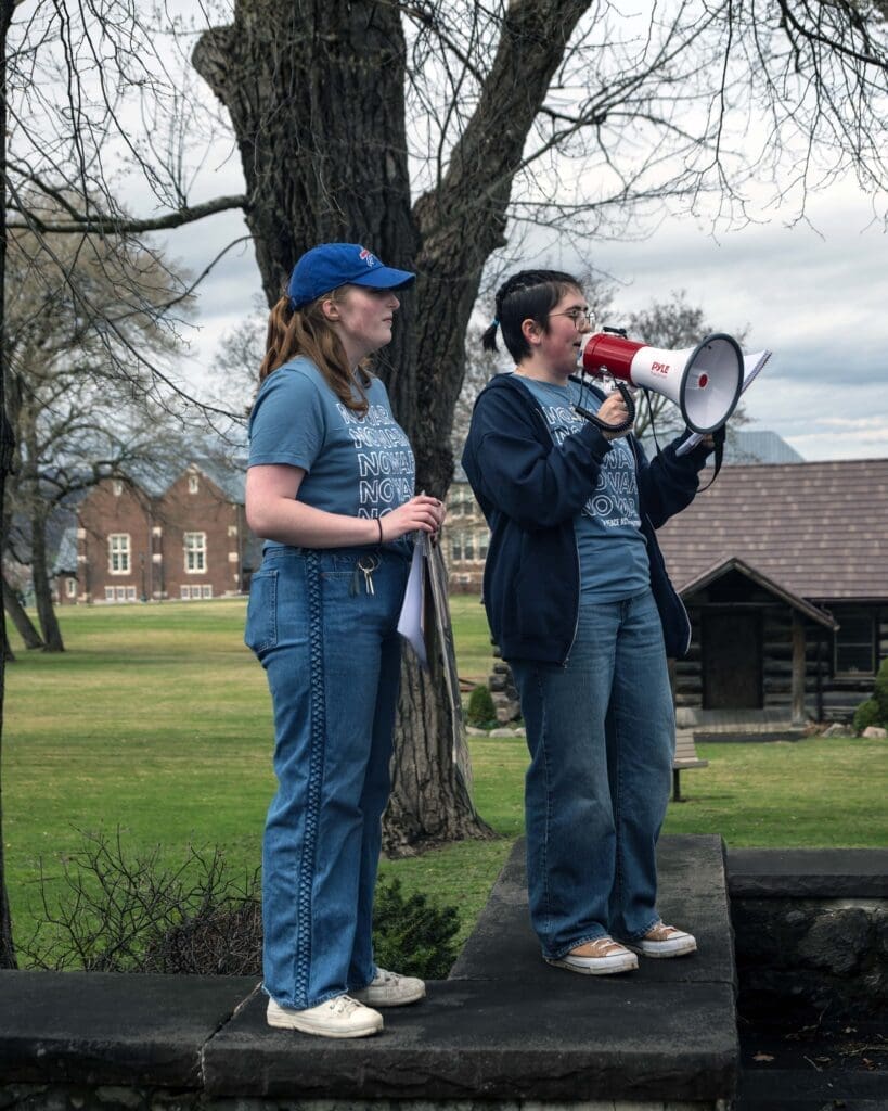 Speakers with megaphone outside on a raised platform.