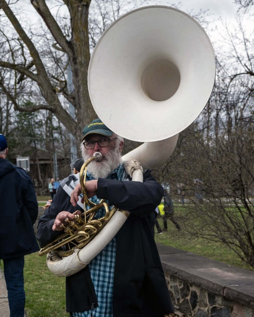 Man plays sousaphone in outdoor setting.