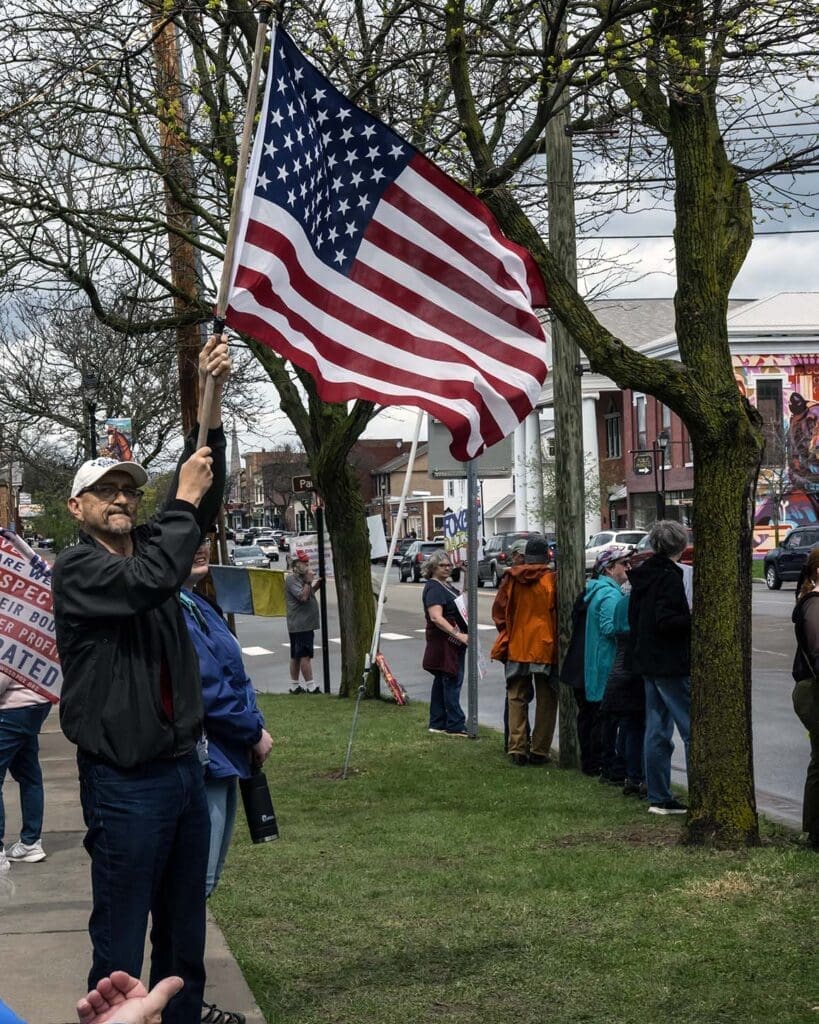 Person holding an American flag in a street protest.