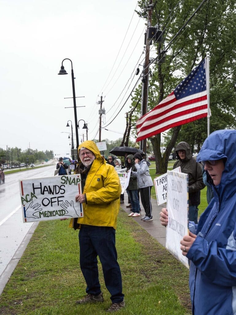 Protesters holding signs in the rain.