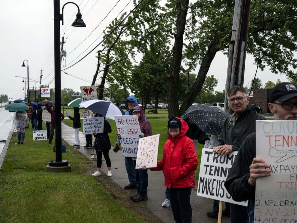 Protesters holding signs in the rain.
