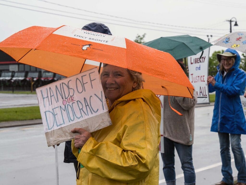 Protesters holding signs in the rain.