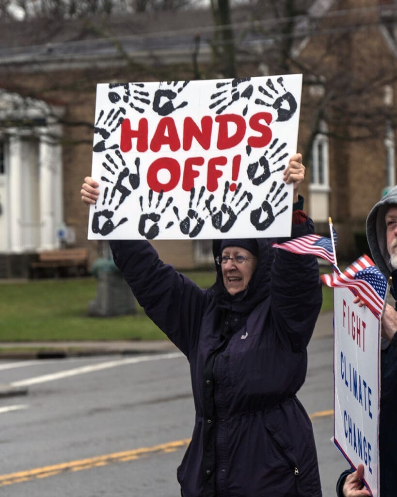 person holding a sign that says hands off!