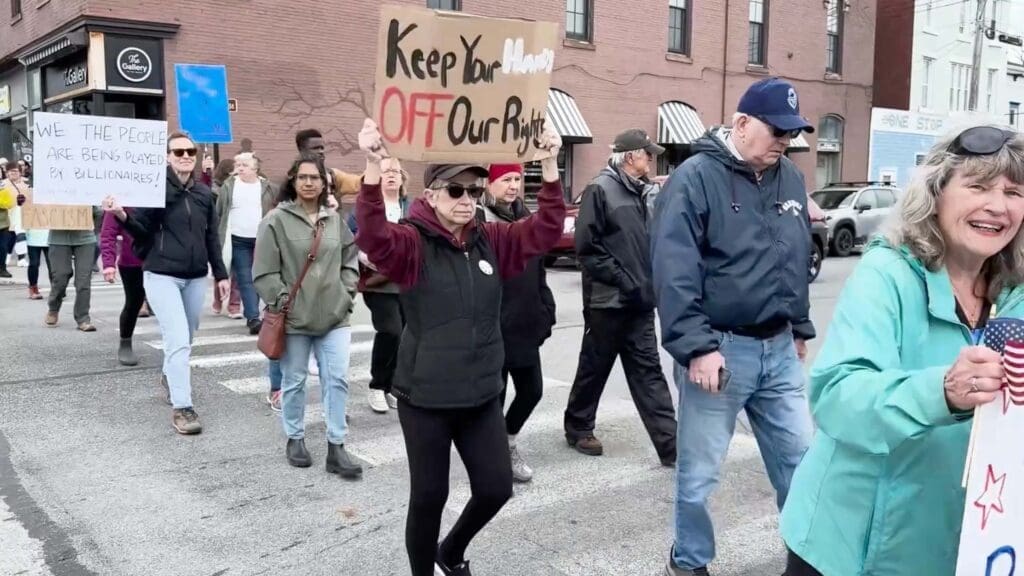 Protesters marching with signs in a street demonstration.