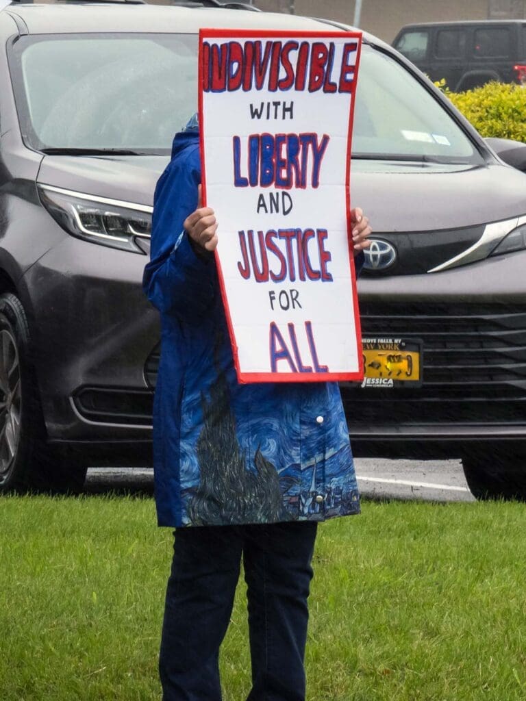 Person holding sign about liberty and justice.