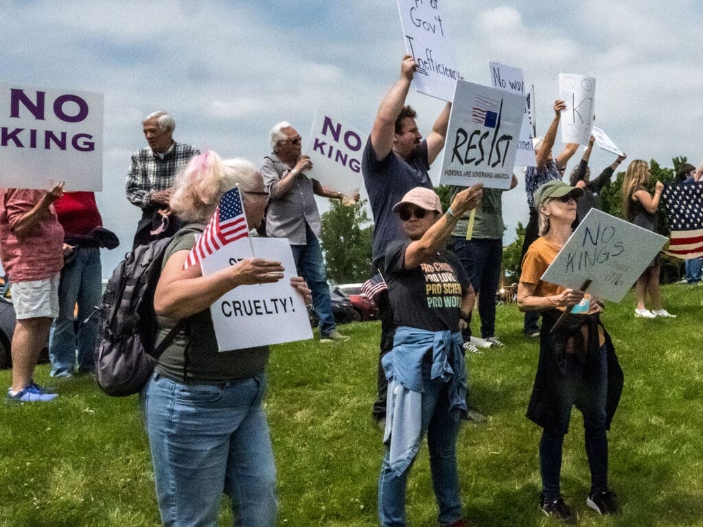Protesters holding signs on a grassy area.