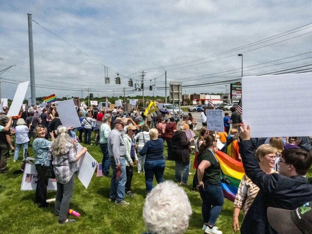 Crowd holding signs at a peaceful protest rally.