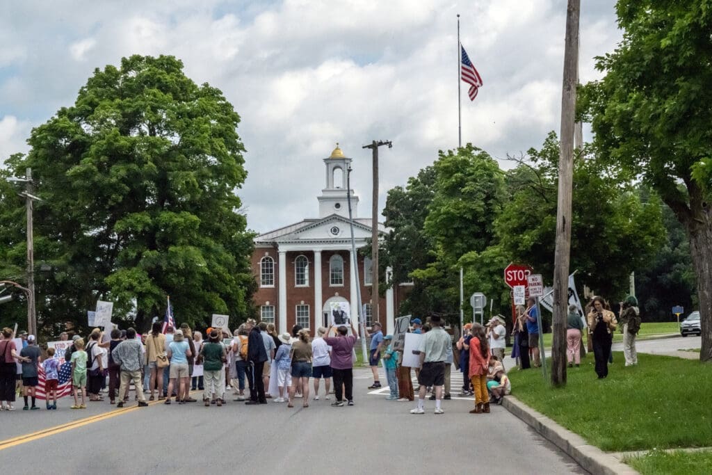 Protesters gather outside a historic building with signs.