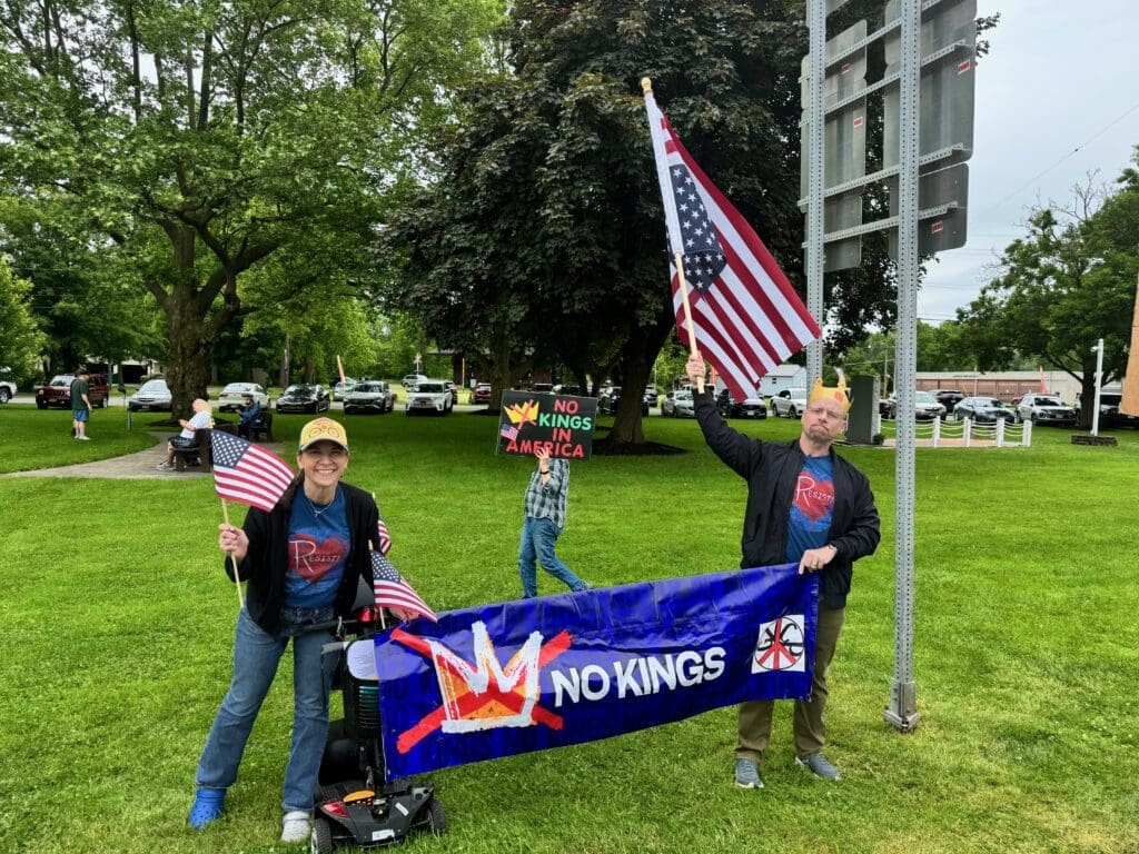Protesters holding American flags and 'No Kings' banner.