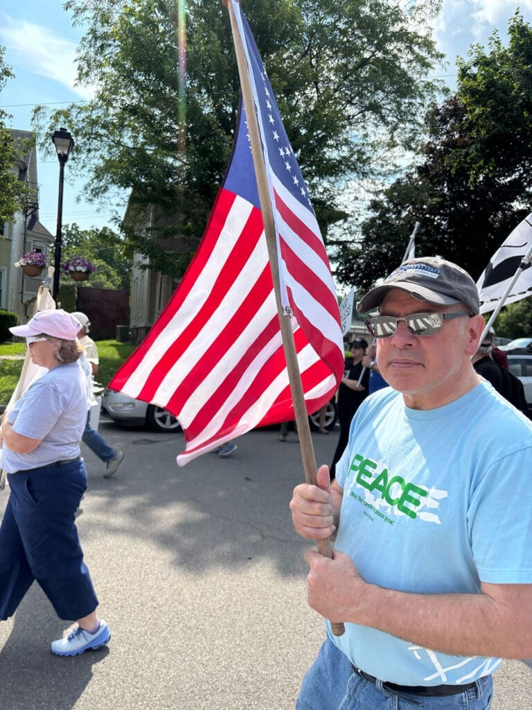 Man holding American flag at peaceful protest.