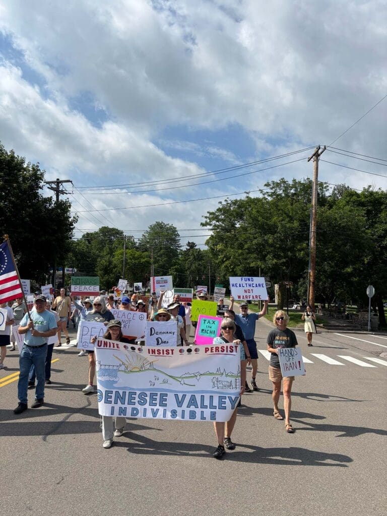 Protest march with signs and banner on street.