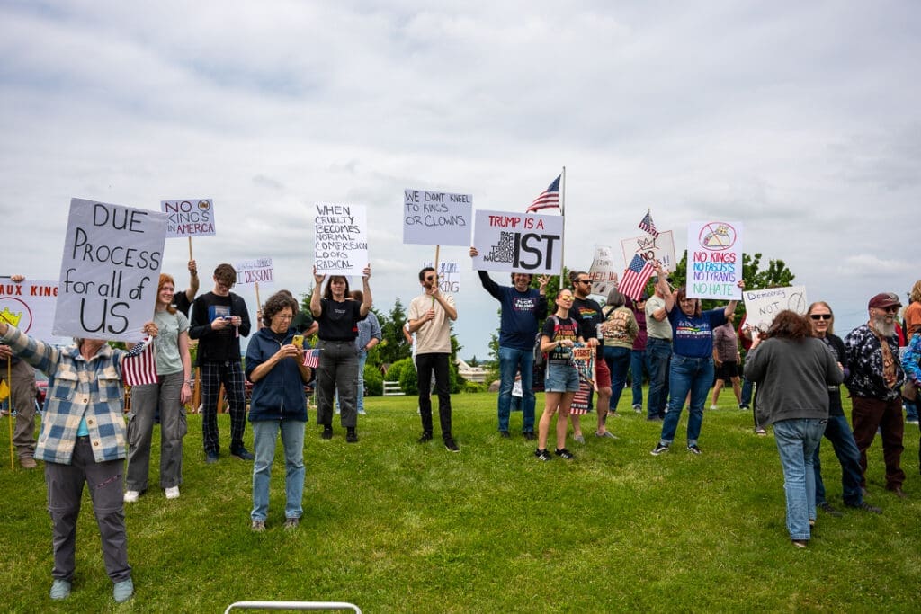 Protesters holding signs on a grassy area.