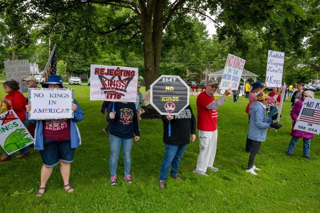 Protesters holding signs against monarchy in America.