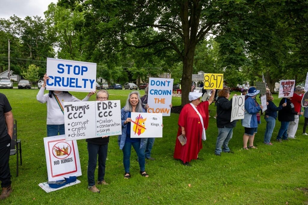 People protesting with various signs in a park.