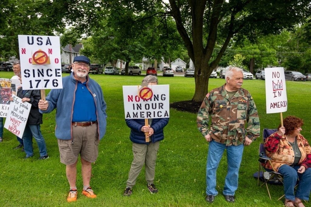 Protesters with anti-monarchy signs in a park.