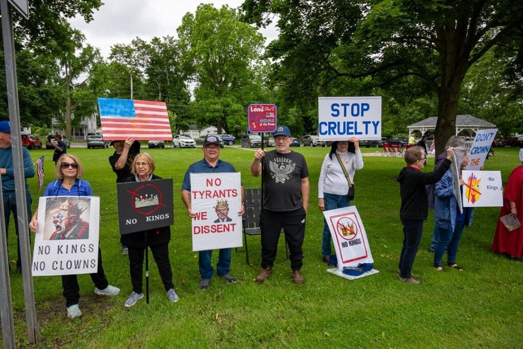 Protesters holding signs against tyranny in a park.