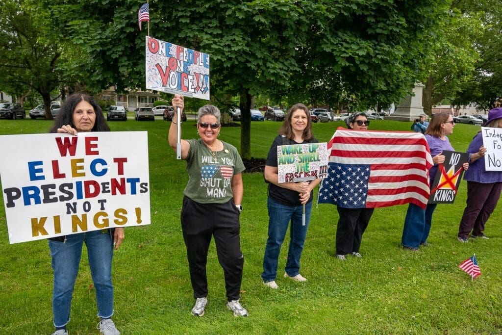 Protesters with signs in a park demonstration.