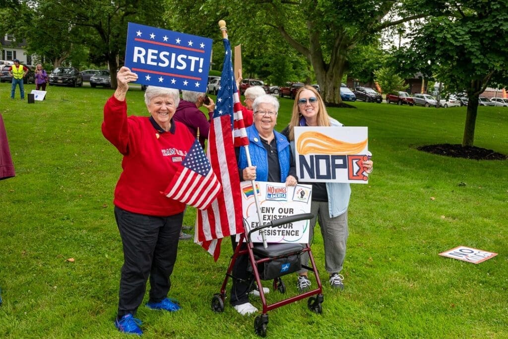 Protesters holding signs advocating resistance, outdoors.