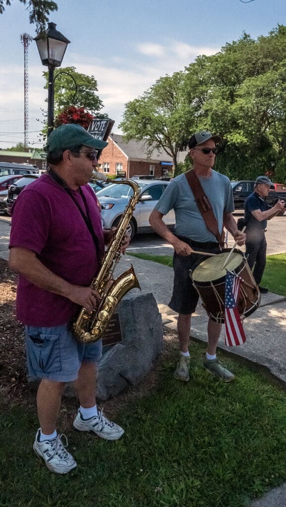 Musicians playing saxophone and drum in park.