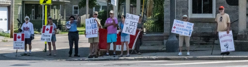 People holding protest signs on a street corner.