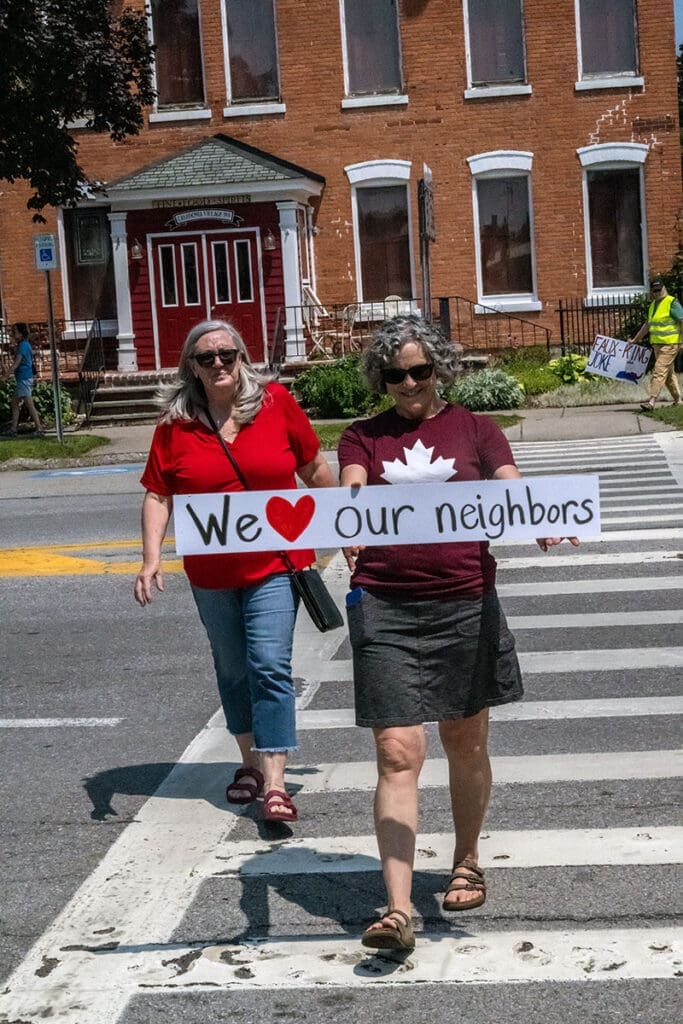 Two women holding 'We love our neighbors' sign