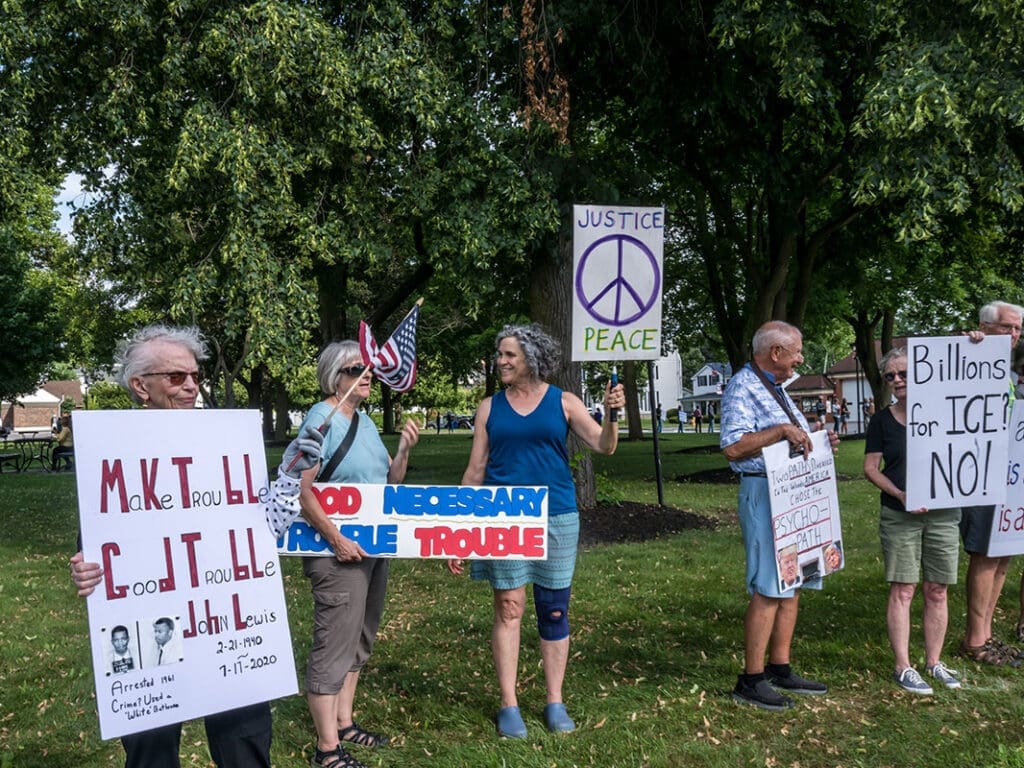 People holding protest signs in a park.