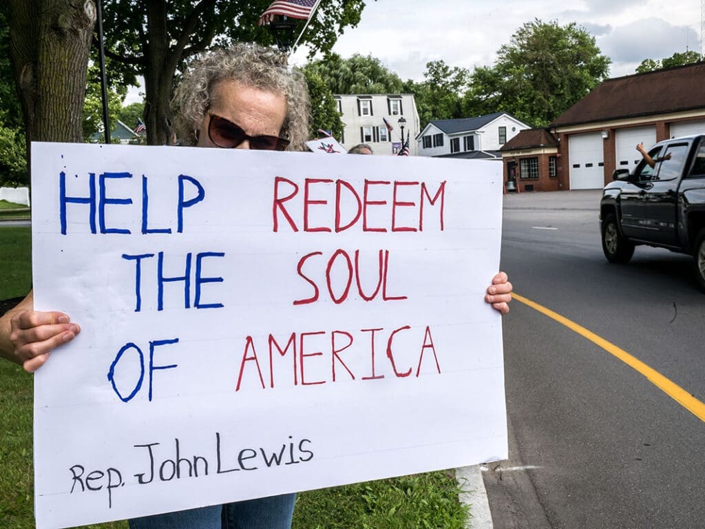 Person holding 'Help Redeem the Soul of America' sign.
