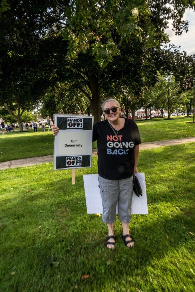 Person holding protest sign at outdoor rally.