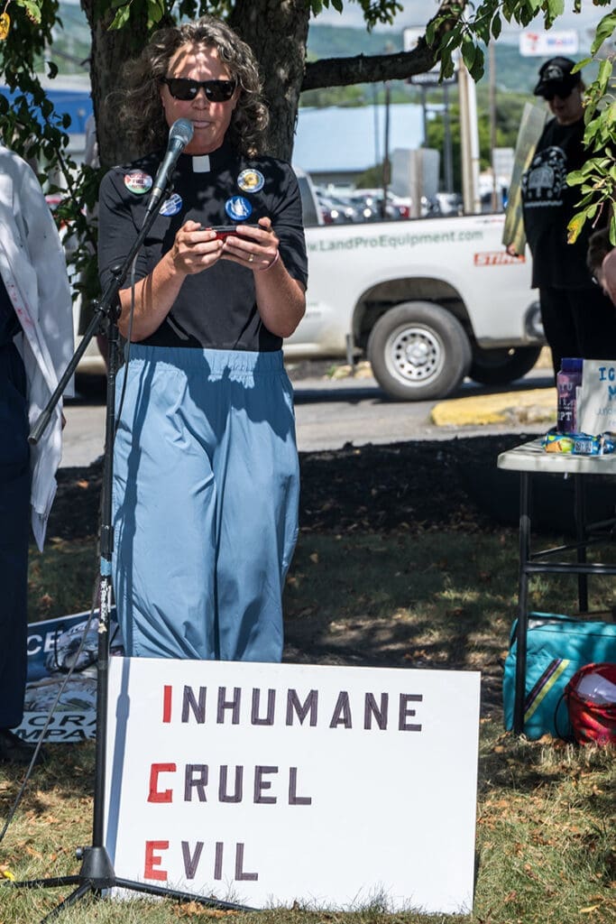 Person protesting with ICE sign in outdoor event.