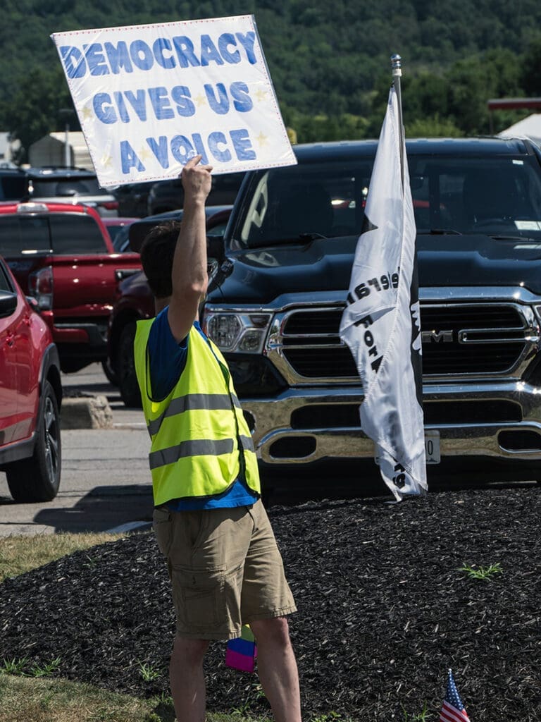 Protester with sign: Democracy gives us a voice.