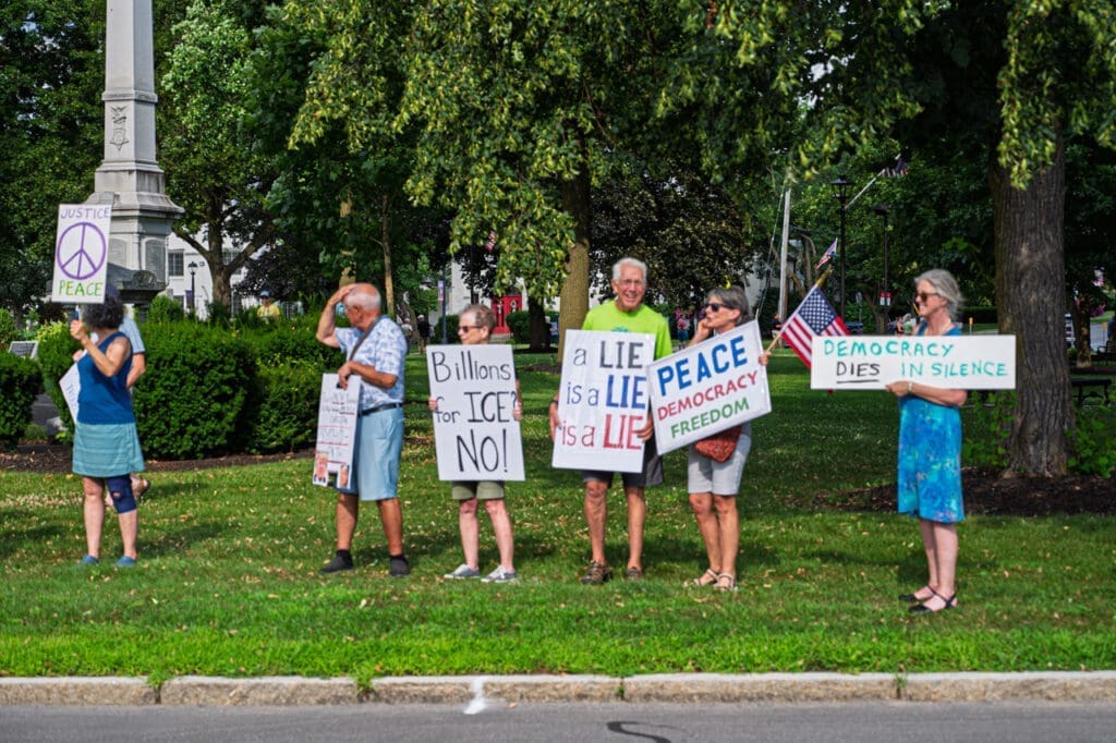 Protesters hold signs advocating for peace and democracy.