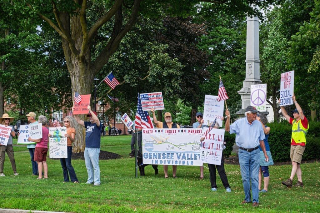 Protesters holding signs and flags at a rally.