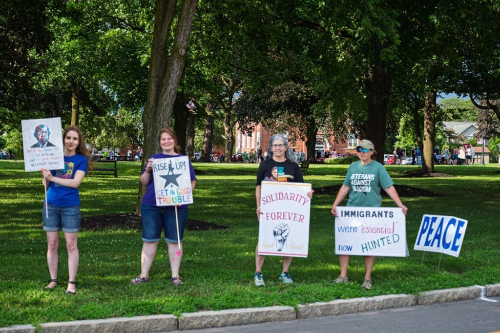 Group holding protest signs in park.