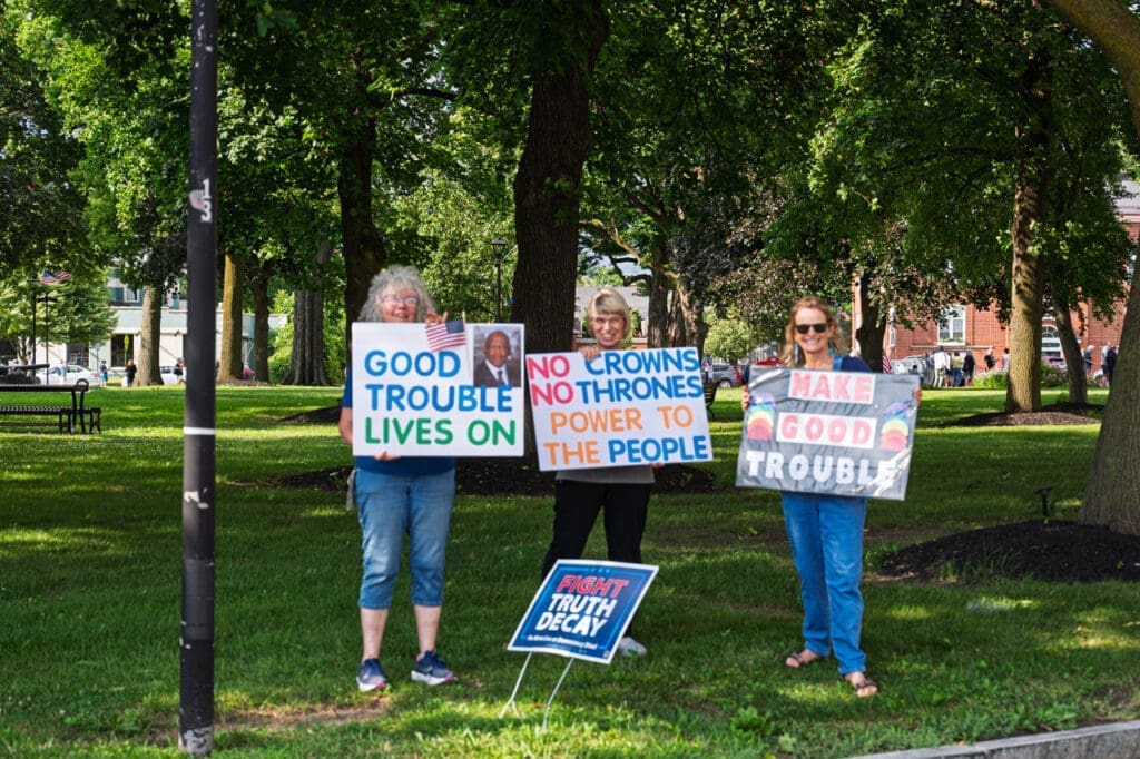 Protesters holding political signs in park.