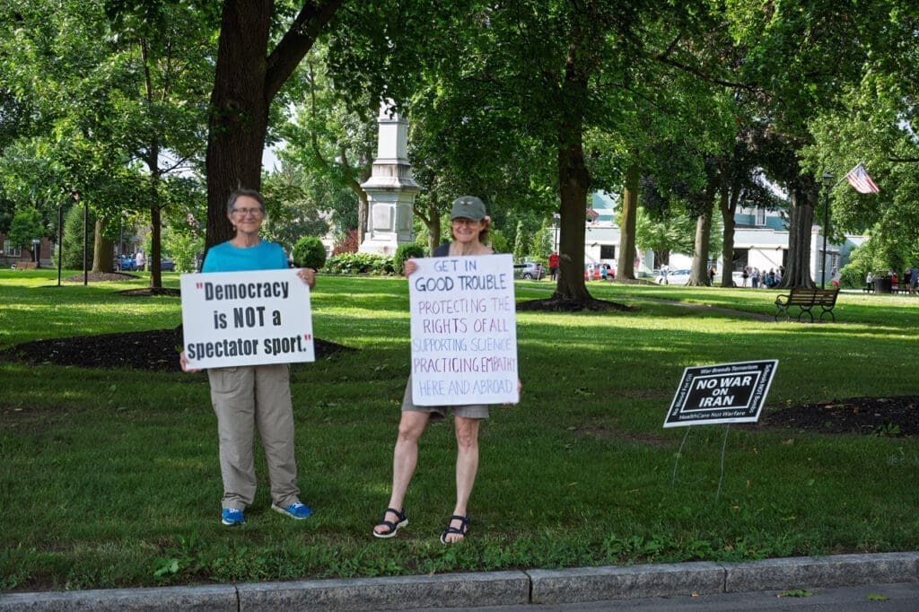 People holding protest signs in a park.