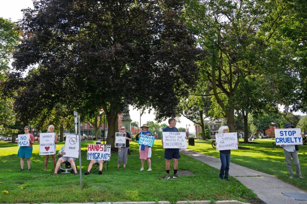 Protesters holding signs in a park.