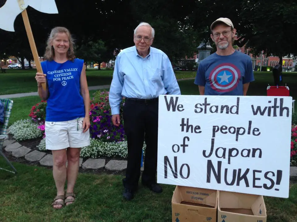 Protesters support Japan, holding "No Nukes" sign.
