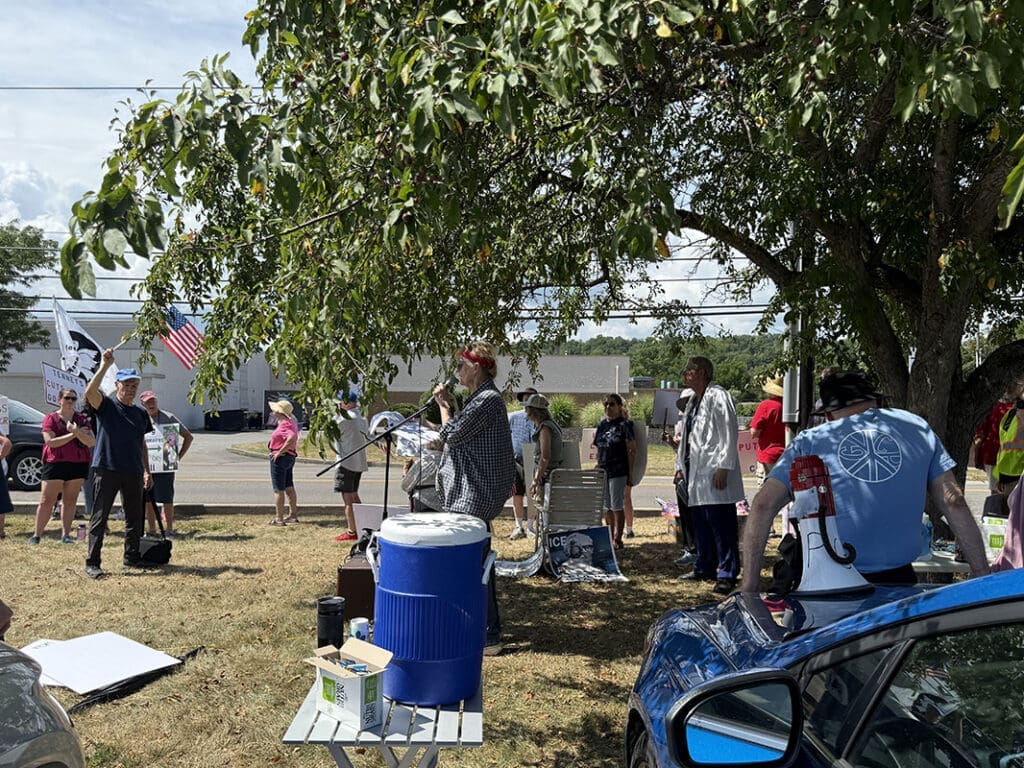 Outdoor protest with people holding signs and flags.
