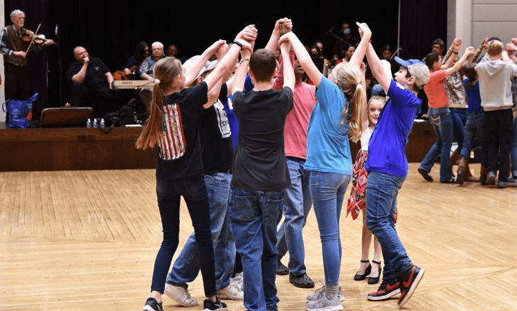 Group of people dancing in a circle indoors.