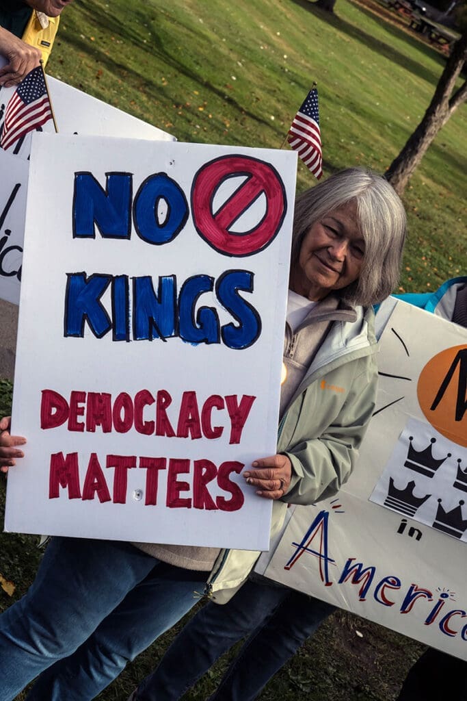 Protester holds sign saying 'No Kings, Democracy Matters'.