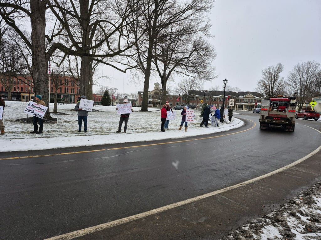People holding signs protest on snowy street.