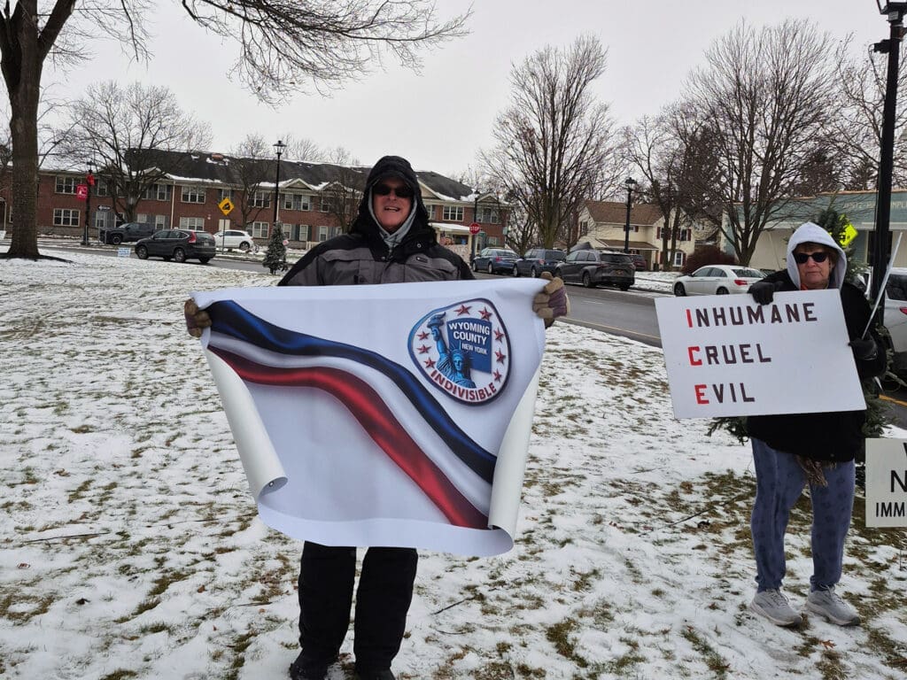 Protesters hold signs in snowy park.