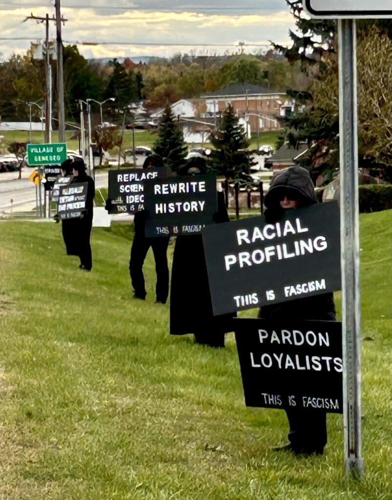 Protesters holding anti-fascism signs on grass.