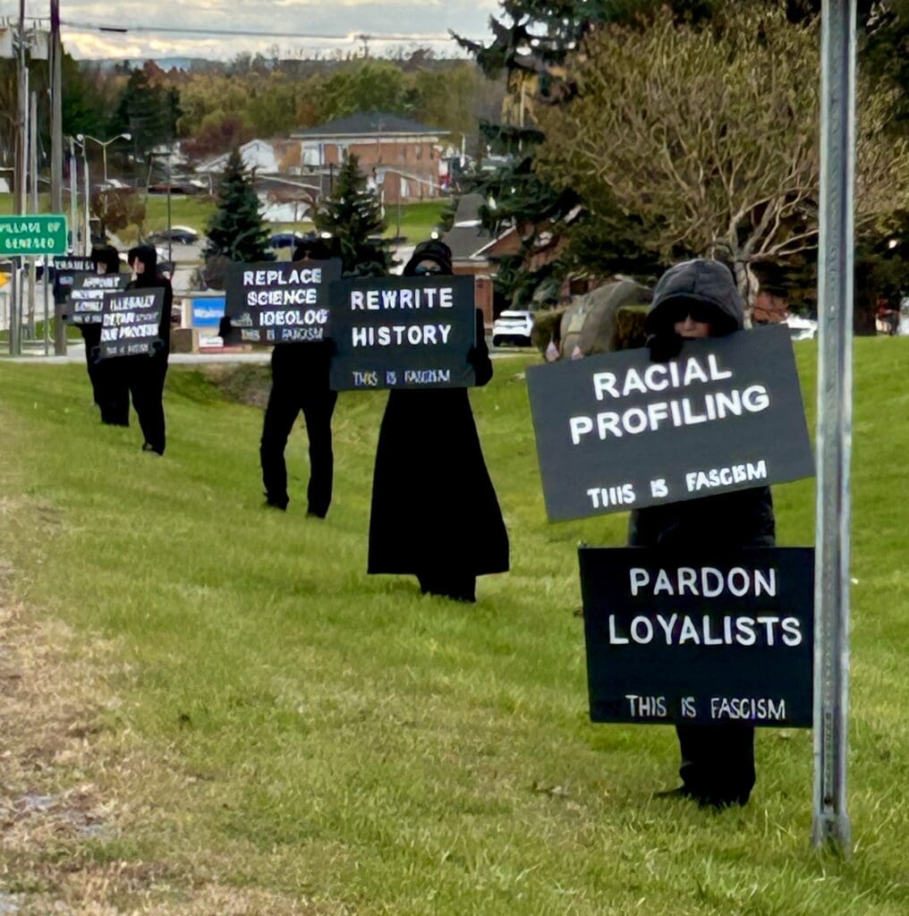 Protesters with signs about fascism standing in line.