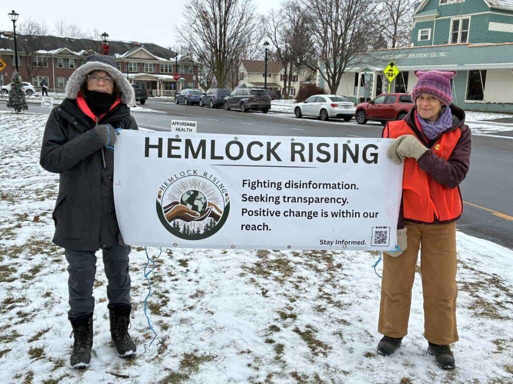 Women holding Hemlock Rising protest banner in winter.