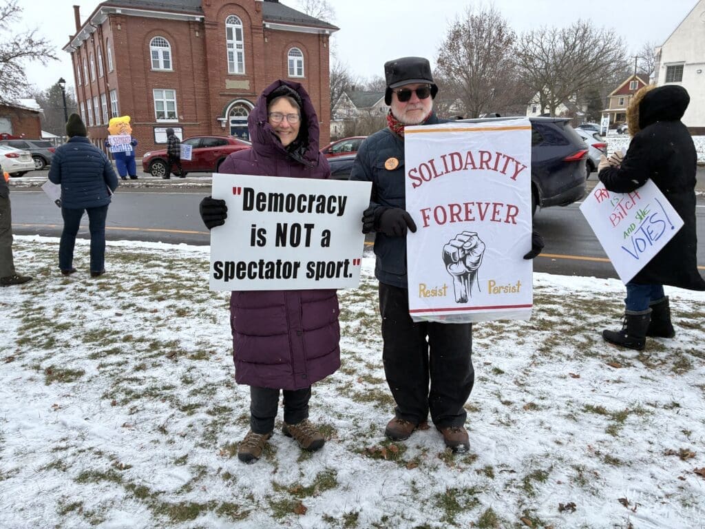 People holding protest signs in snowy park.