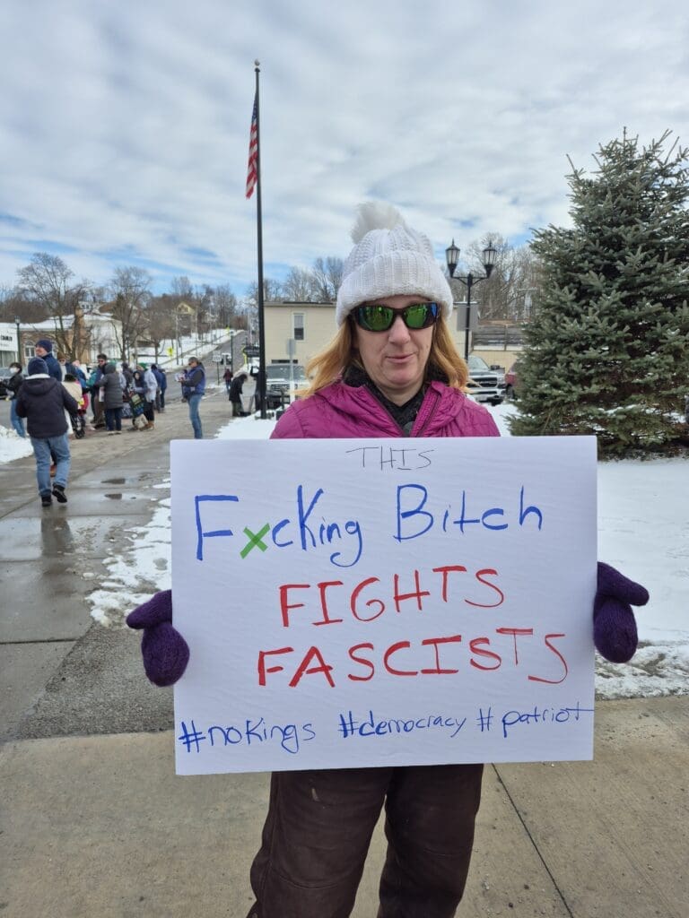 Person holding sign protesting fascism outdoors.