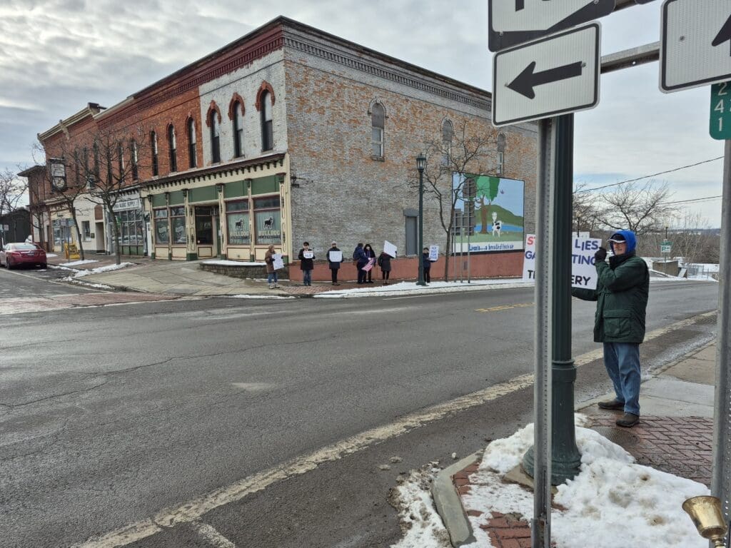 Protesters holding signs on snowy street corner.