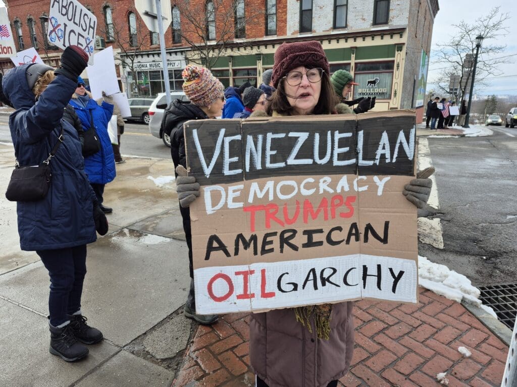 Protesters holding signs on a snowy street corner.